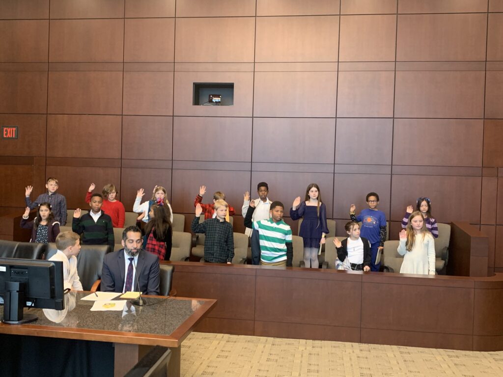 A group of students in a jury box being sworn in