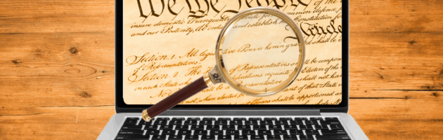 The U.S. Constitution visible on a laptop screen under examination of a magnifying glass