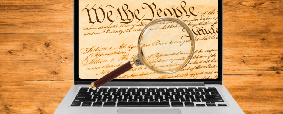 The U.S. Constitution visible on a laptop screen under examination of a magnifying glass